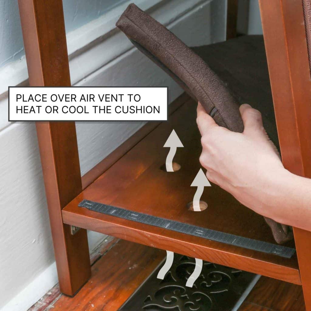 A person sets an A Frame Wooden Cat Bed Scratching Post on a shelf above a floor vent, with arrows showing airflow direction.