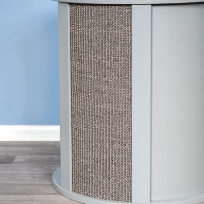 Close-up of a cylindrical light gray end table part with sisal texture, set before a blue wall and wood-patterned floor.