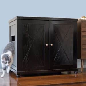 Gray and white cat stepping out of a dark wood cabinet-style litter box with double doors on a wooden floor.
