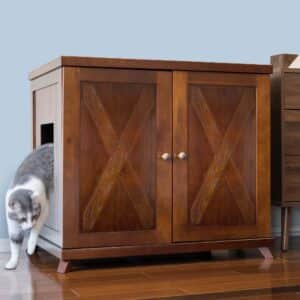 Gray and white cat exiting a double-door litter box cabinet with side entrance, on a hardwood floor.