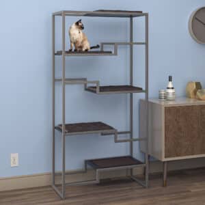 Siamese cat on top platform of gray metal cat tower with brown cushion, against a light blue wall in modern living room.