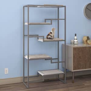Cat sitting on a metal and wood cat condo with gray frame, white platform, gray cushion; near a cabinet and wall clock.