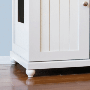 White wooden cabinet with paneled door and round knob, on four tulip-style feet, on wood floor against light blue wall.