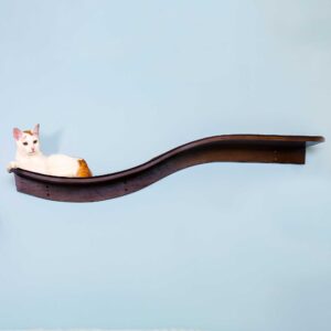 A white and orange cat lounges on a mahogany wave-shaped wall shelf resembling a branch, against a light blue background.