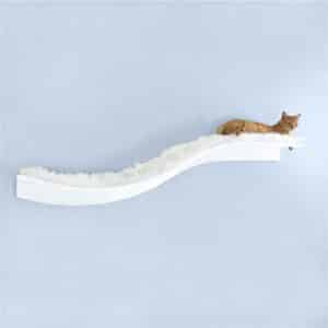 A cat resting on a white, fluffy Lotus Branch Cat Shelf mounted on a wall, with a light blue wall in the background.