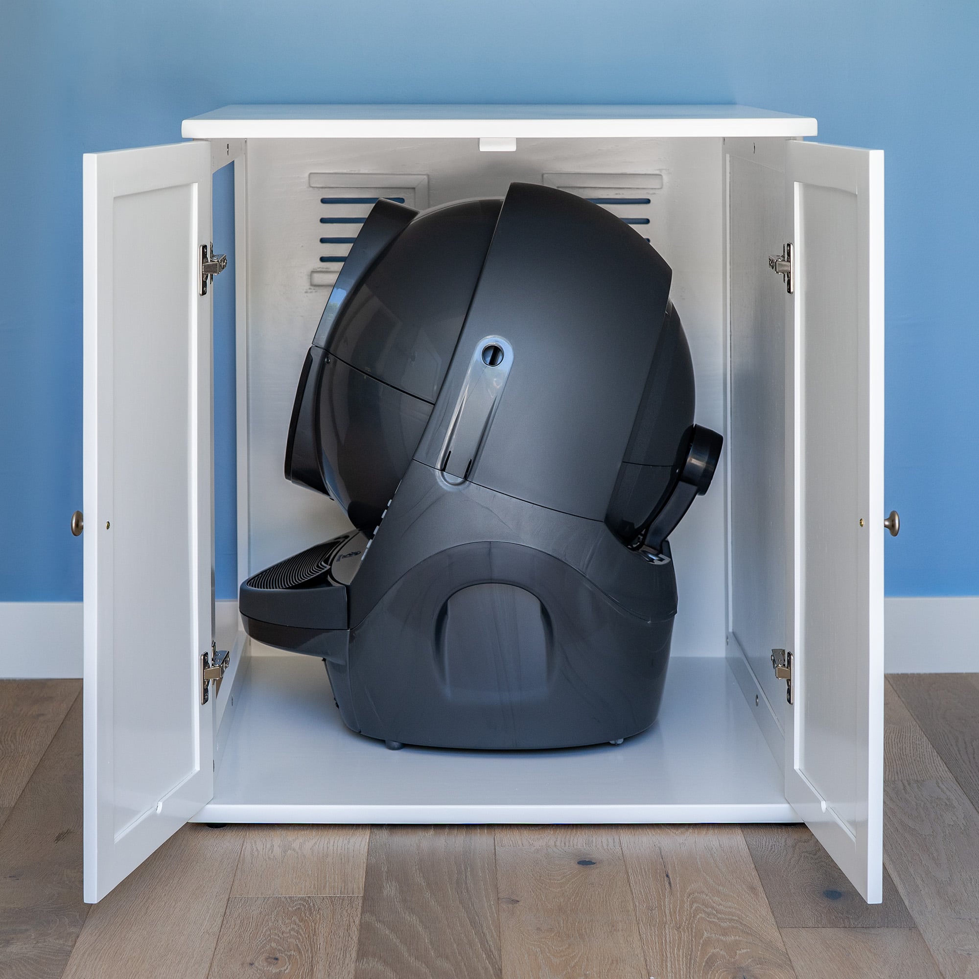 A black DSC09086 self-cleaning litter box inside an open white cabinet, set against a blue wall and light wood floor.