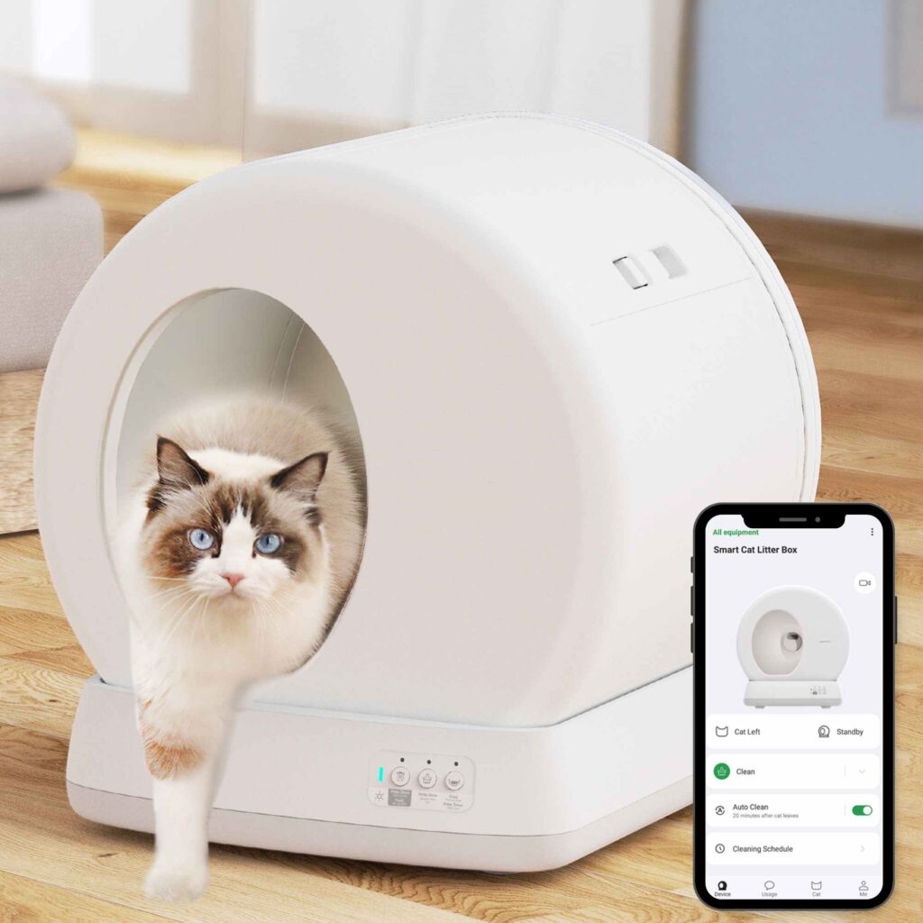 A cat steps out of a white self-cleaning litter box; a nearby smartphone displays the litter box control app screen.