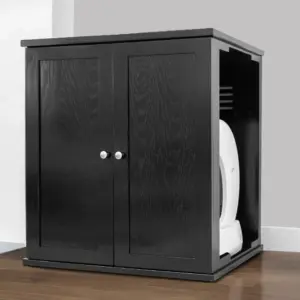 Black wooden litter box cabinet with two doors on wood floor, gray wall, part of white appliance visible inside.
