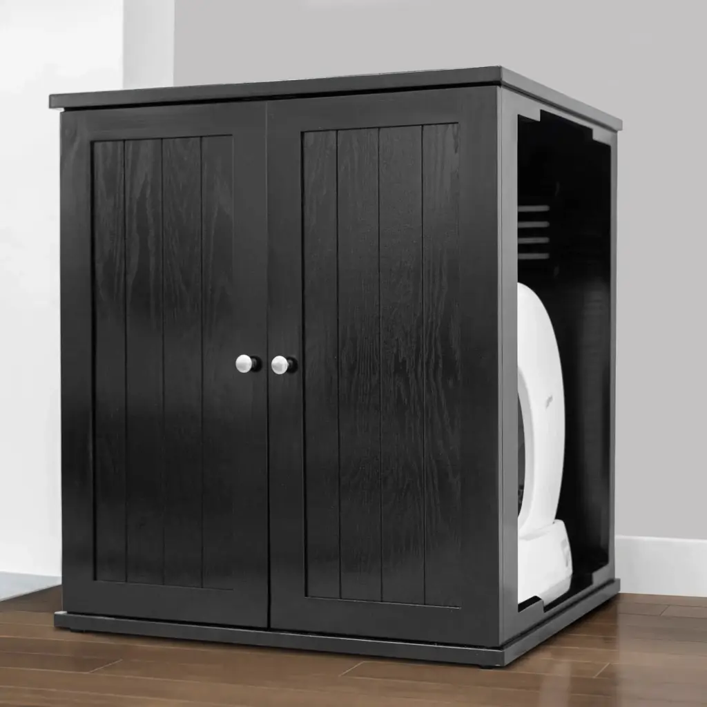 Black wooden litter box cabinet, two doors ajar showing self-cleaning litter box, on wood floor near light gray wall.