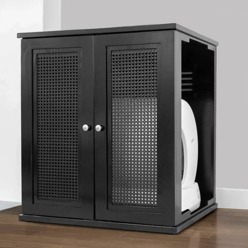 Black wooden litter box cabinet with mesh doors on a wooden floor, against a gray wall, concealing self-cleaning box.