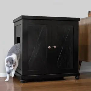 Gray and white cat steps out of a black wooden cabinet with side entrance on a hardwood floor near furniture.