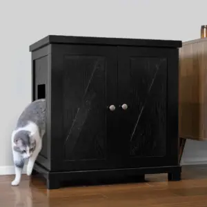 Gray and white cat stepping out of a black cabinet with double doors on a wooden floor beside another cabinet.