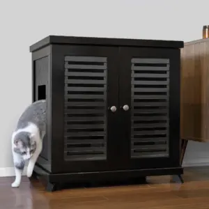 Gray and white cat exiting a black wooden cabinet with two slatted doors, against a pale wall and wood floor.