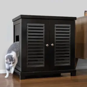 Gray and white cat stepping out of a black cabinet with slatted doors on hardwood floor beside another piece of furniture.