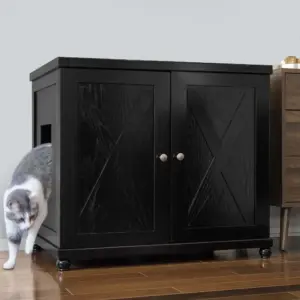 Gray and white cat exits a black wooden cabinet with double doors on a wood floor next to another furniture piece.