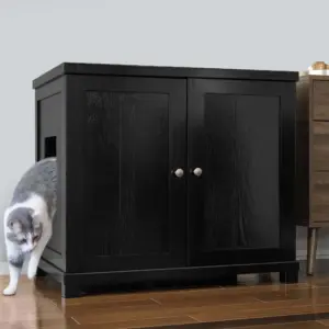 Gray and white cat exiting a black wooden cabinet with a side opening, on wooden floor next to a brown side table.