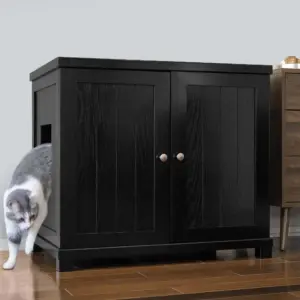 Gray and white cat exits a black wooden cabinet with double doors, on a wooden floor beside a brown nightstand.