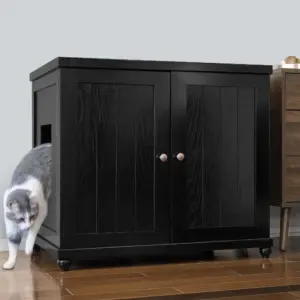 Gray and white cat walks out of a black cabinet with side opening, on wooden floor next to brown furniture.