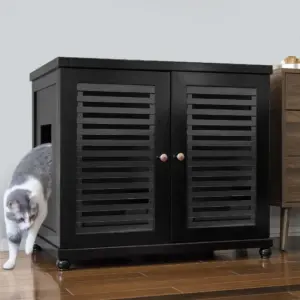 Gray and white cat steps out of a black cabinet with slatted doors and round side entry, on wood floor by brown drawer unit.
